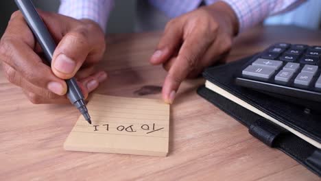 person writing a to-do list at a desk