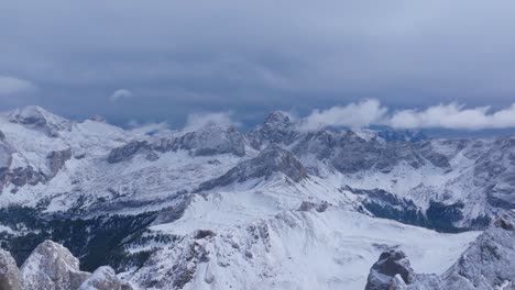 aerial drone shot showing wide view of snow covered mountain range with rugged peaks, cloudy sky, and forest patches in west virginia, america, during cold winter season in remote wilderness