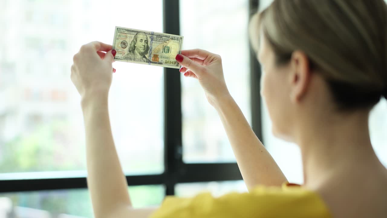 Woman inspecting a 100 dollar bill