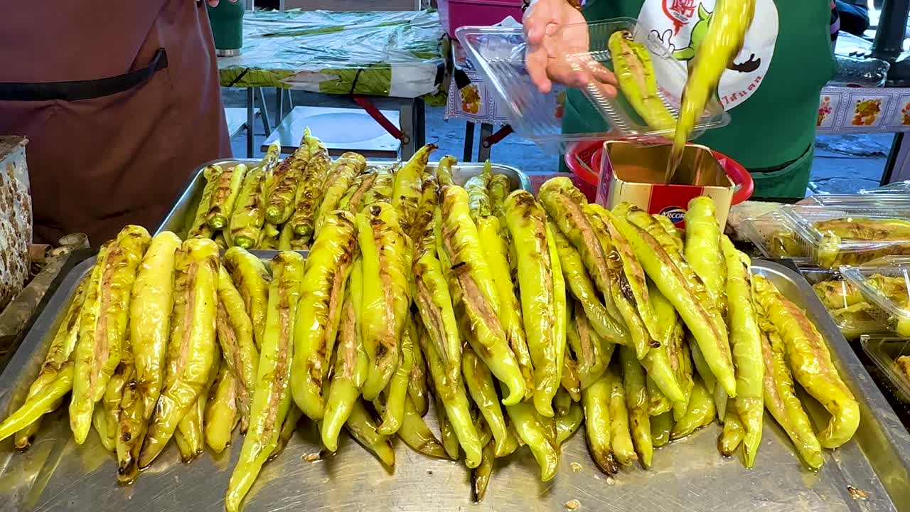 Vendor preparing grilled green peppers for sale