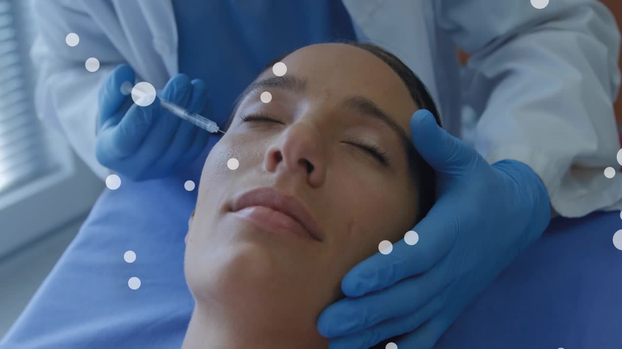 Clinico che tiene delicatamente il viso del paziente e guida una siringa nella guancia per il rimodellamento con cerchi bianchi.