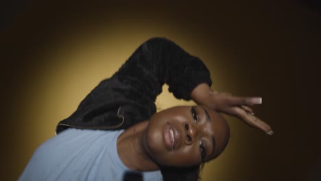 head and shoulders studio portrait shot of young woman dancing in spotlight against yellow background 7