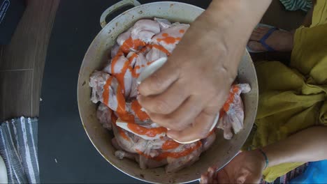 female pouring sauce onto chicken pieces in casserole pan and marinating it