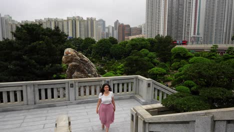 woman climbing stairs in nan lian garden terrace and hong kong cityscape in background