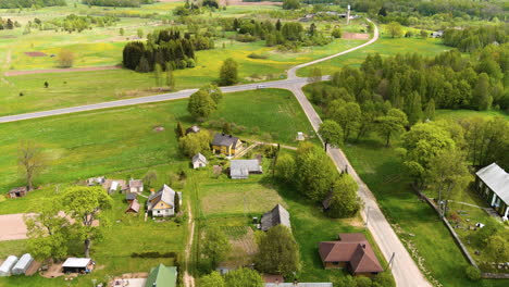 aerial view of rural village in countryside of lithuania, homes and farming land on summer season, drone shot