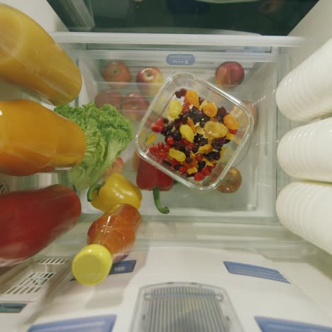 midnight snack view from inside the refrigerator - women's hands take sweets from a plate