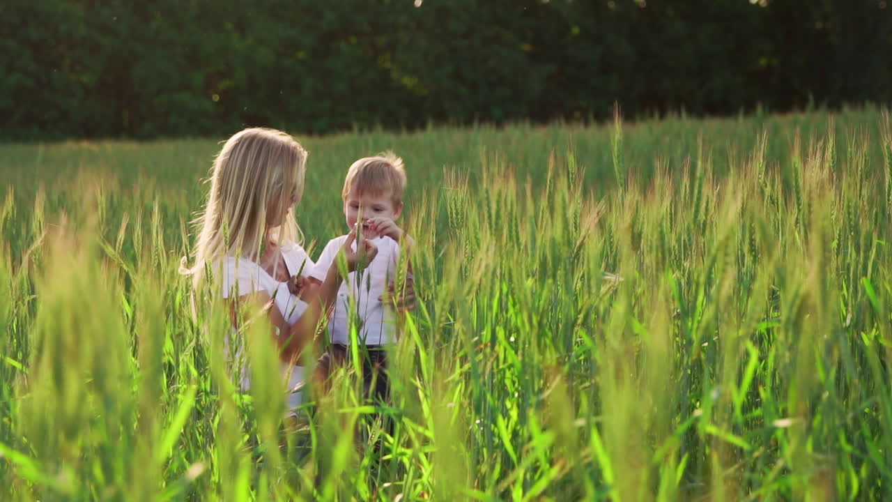 счастливая семья веселится. мальчик с коричневыми кудрявыми волосами и его мать с рыжими волосами показывают палец друг другу. съемка на открытом воздухе