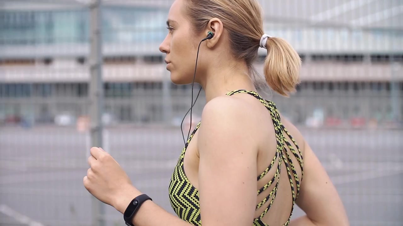 Giovane donna che corre all'aperto con auricolari e smartphone