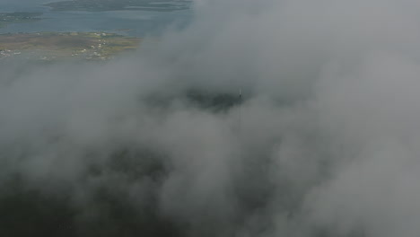 Aerial-reveal-view-of-a-radio-tower-on-top-of-a-cloudy-mountain,-location-Minaun-Heights-on-Achill-Island,-west-coast-of-Ireland