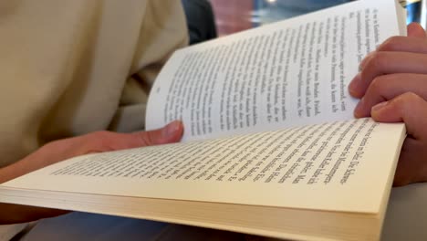 primer plano de una persona femenina sosteniendo un libro y leyendo en interiores en una biblioteca tradicional