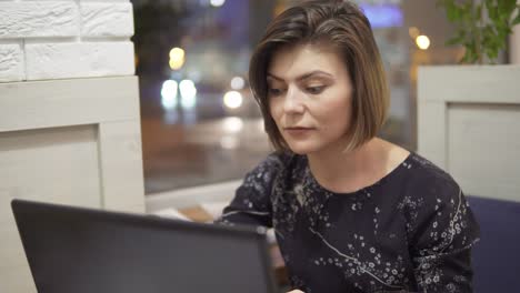 joven mujer de negocios sentada junto a la ventana con una computadora portátil y trabajando