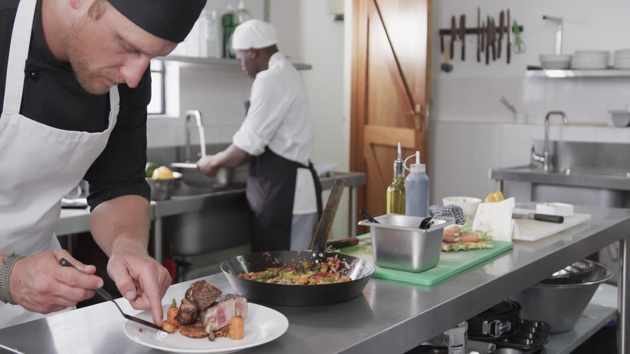Due chef uomini di diverse etnie che preparano pasti in cucina, slow motion