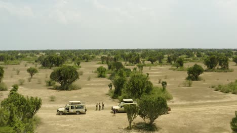 jeeps de safari estacionados en medio de la reserva natural de uganda con árboles y arena de repuesto