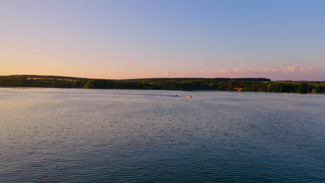 beautiful evening landscape over the water. motor boat floating at orange sunset. people travelling in high-speed boat under clear sky.