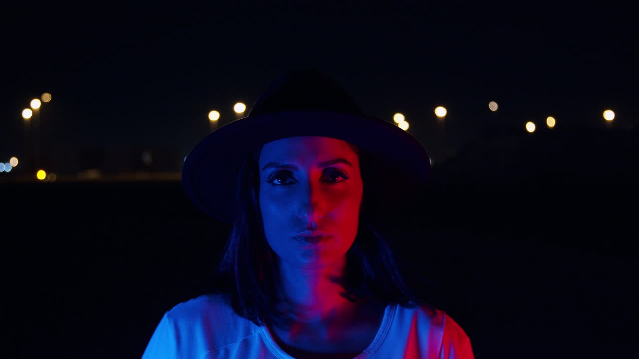mujer hipster mirando a la cámara con luz azul cambiando a rojo - toma de primer plano