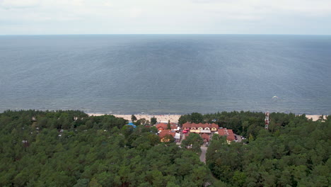 Toma-Aérea-De-Establecimiento-De-La-Playa-De-Stegna,-Vista-Sobre-Los-árboles,-La-Franja-Arenosa,-El-Océano-Y-El-Horizonte