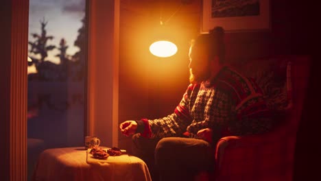 portrait of a man eating while sitting on a couch with a lamp at home