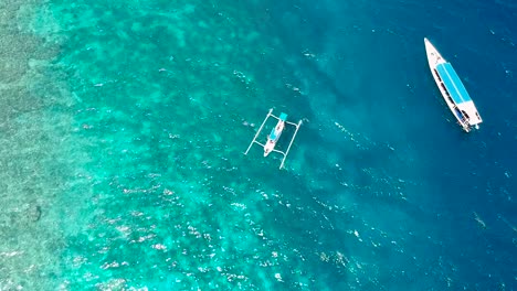 Toma-Aérea-De-Una-Canoa-Indonesia-Tradicional-Para-El-Buceo-Jukung-Que-Se-Encuentra-Frente-A-La-Costa-Tropical-De-Las-Islas-Gili-Y-Está-Rodeada-De-Aguas-Cristalinas-Y-Coral-En-Indonesia