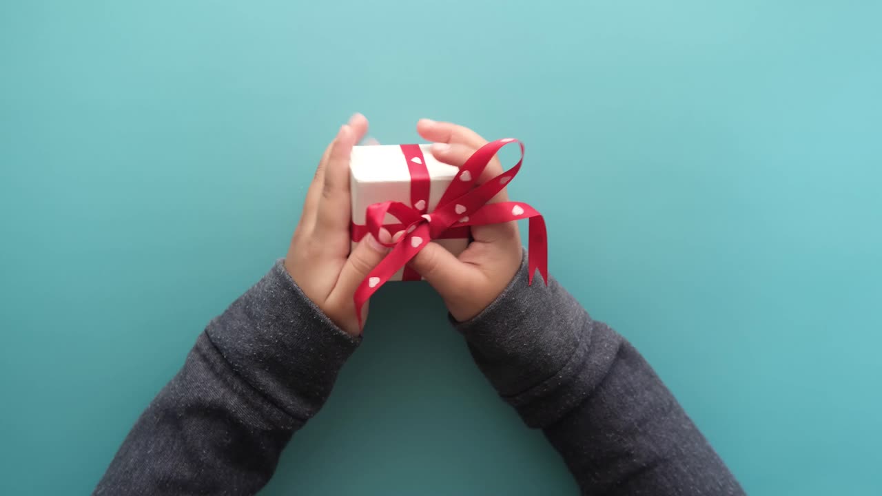 las manos del niño sosteniendo una pequeña caja de regalos