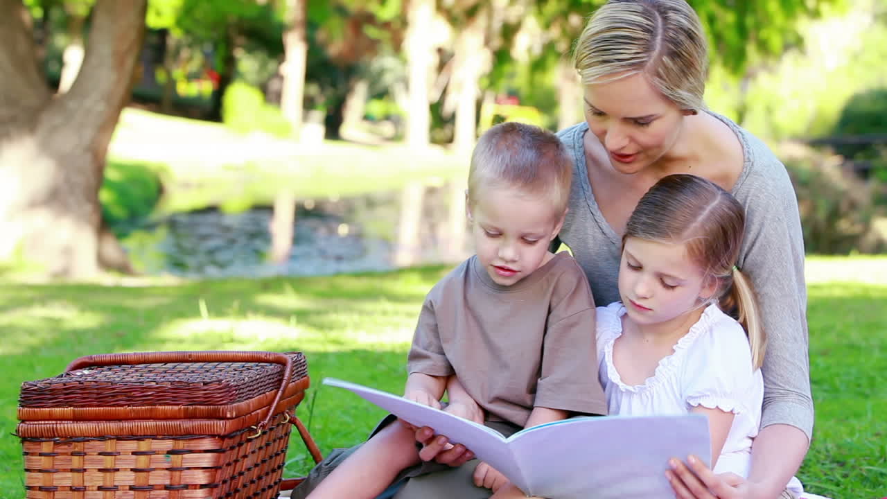 Madre che guarda un libro illustrato con i suoi figli