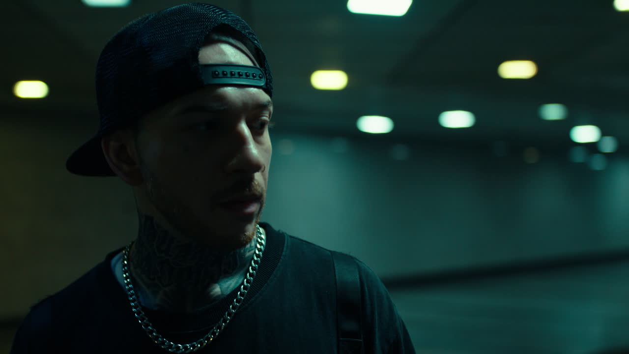 Portrait of a Tattooed Man with a Baseball Cap in a Dark Urban Environment