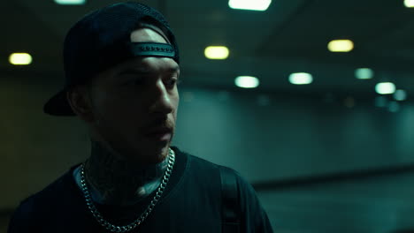 portrait of a tattooed man with a baseball cap in a dark urban environment