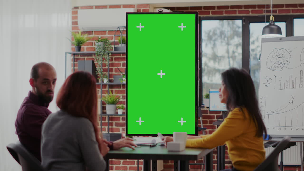 Employees using green screen on monitor vertically in boardroom