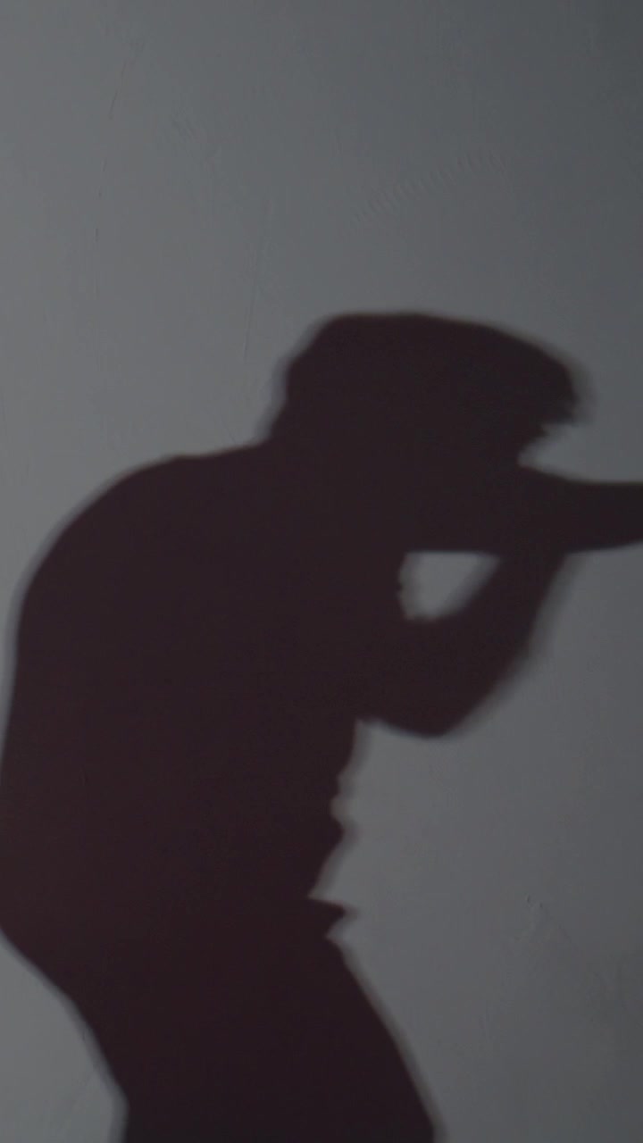 Shadowy figure holds a rifle, aiming forward. Next, the person raises a phone to their ear. Finally, they gesture with one hand, as if speaking or commanding