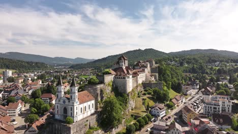 aarburg castle, church and old town along aare river in canton solothurn, switzerland, aerial drone view with scenic green hills in background
