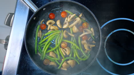 mushrooms and vegetables are fried on the frying pan. smoke comes up to a camera. top view. close up.