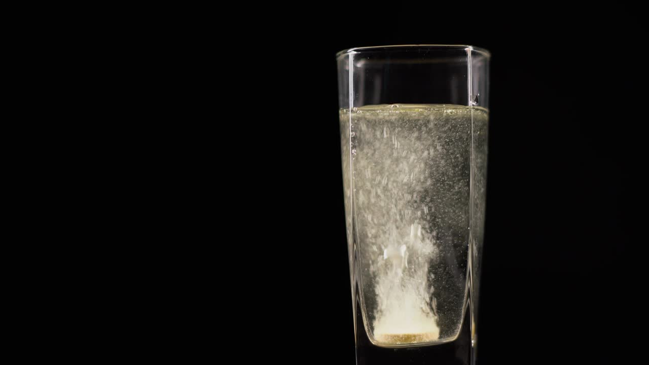 검은 배경에 신선한 미네랄 물 한 잔에 용해 된 비타민 c 태블릿, 검은 배경을 가진 산소 공을 가진 액체에서 버블링 태블릿.