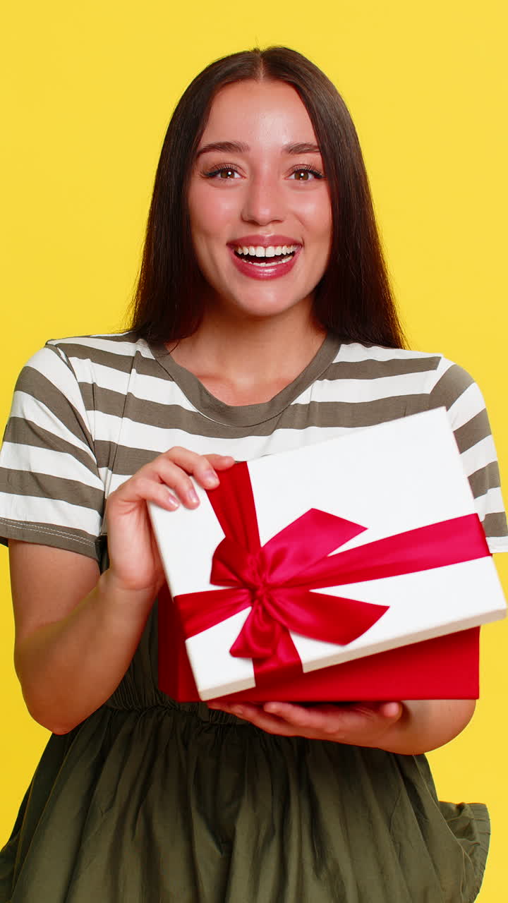 Woman opening birthday gift box with surprised happy expression joyful emotional reaction to present
