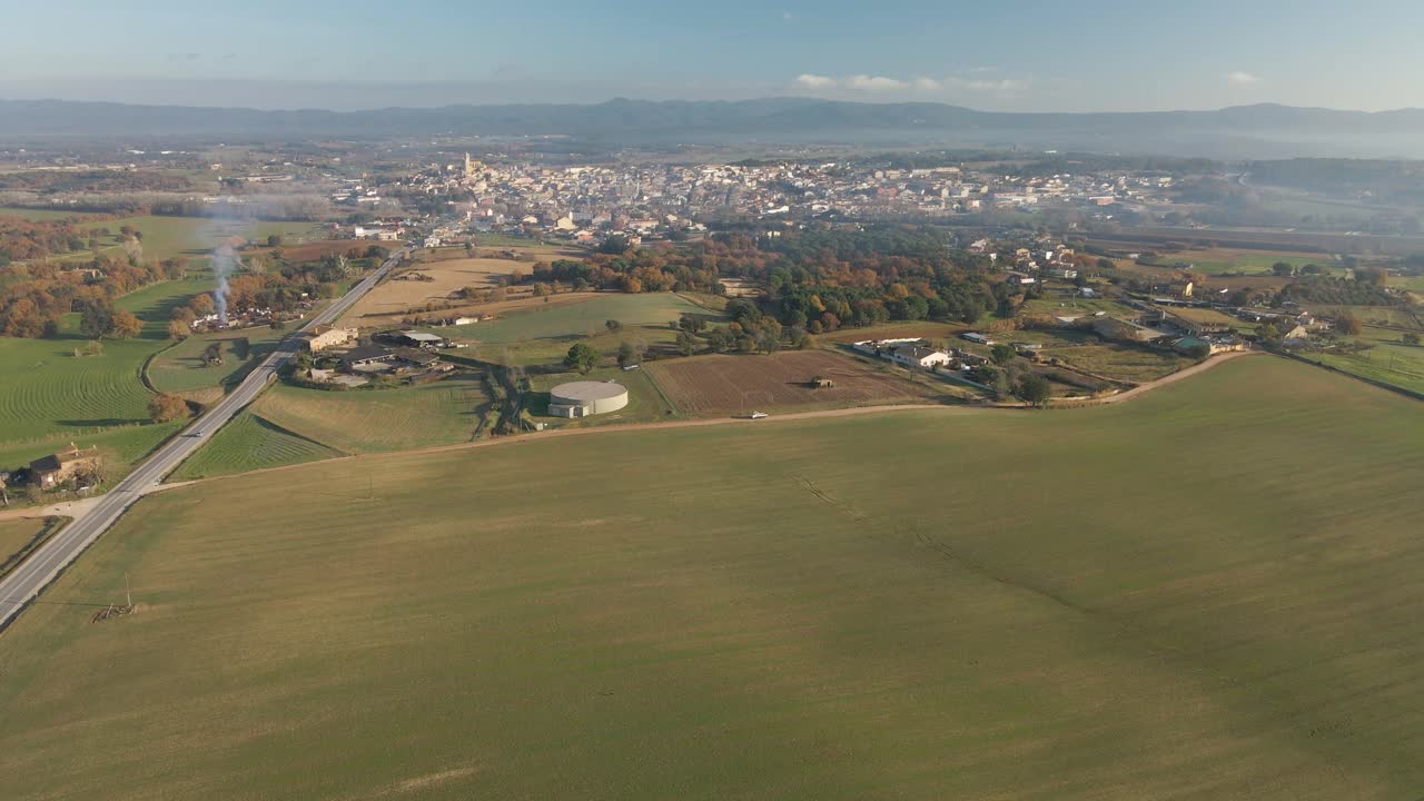 Aerial video of a newly seeded field with a dirt road in the middle and mountains in the background green Llagostera Gerona cultivated field