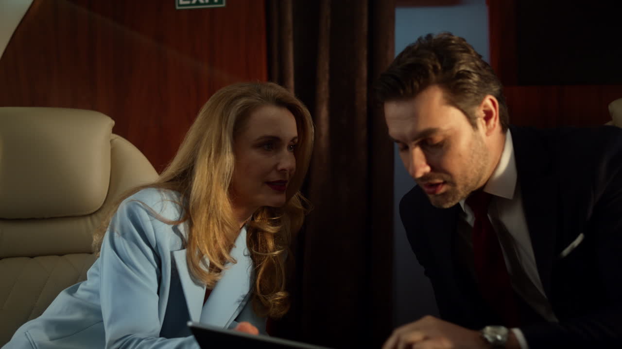 Businesswoman show tablet computer to gentleman in luxury business jet closeup