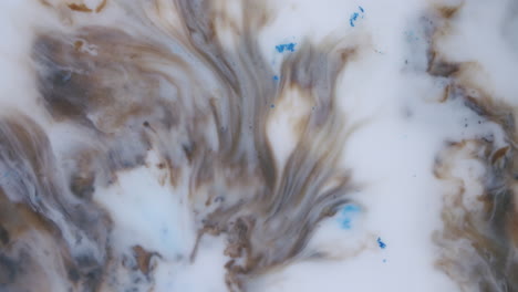 Macro-shot-of-white,-brown-and-blue-liquids-mixing-in-beautiful-shapes-and-patterns