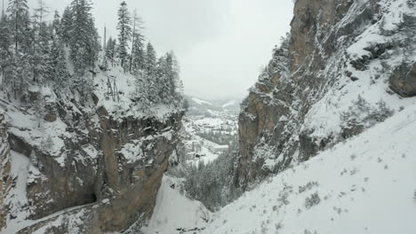 flying between snow covered mountains and revealing a small town in a valley