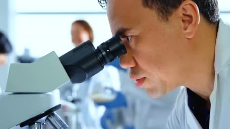 científico masculino usando el microscopio en el laboratorio 4k
