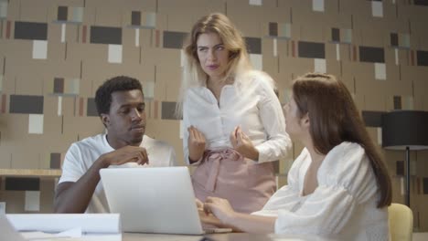 equipo creativo sentado y de pie en la mesa con una computadora portátil