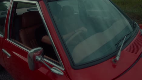 person driving a vintage red car