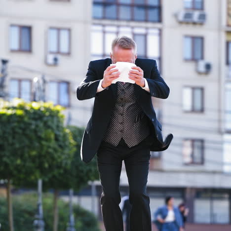 Full length portrait of a senior businessman who finds good news on paper walking in the city. Middle aged person in black suit becomes satisfied after reading outdoors. Slow motion.