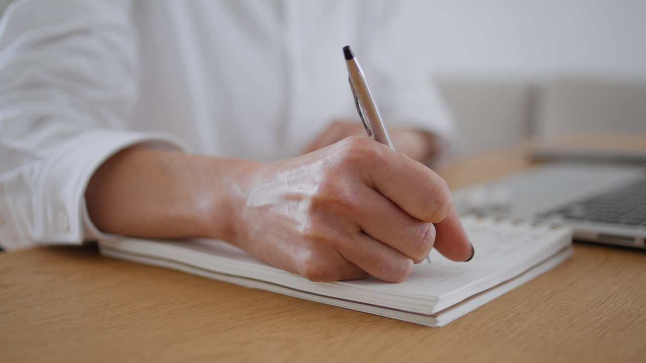 집에서 정보를 기록하는 작가의 손. 책상에서 노트북을 쓰는 여성