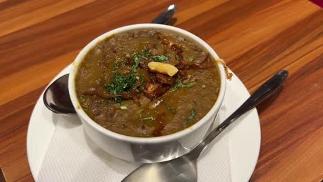 hyderabadi haleem served in a saucer with fried onions and coriander garnishing.