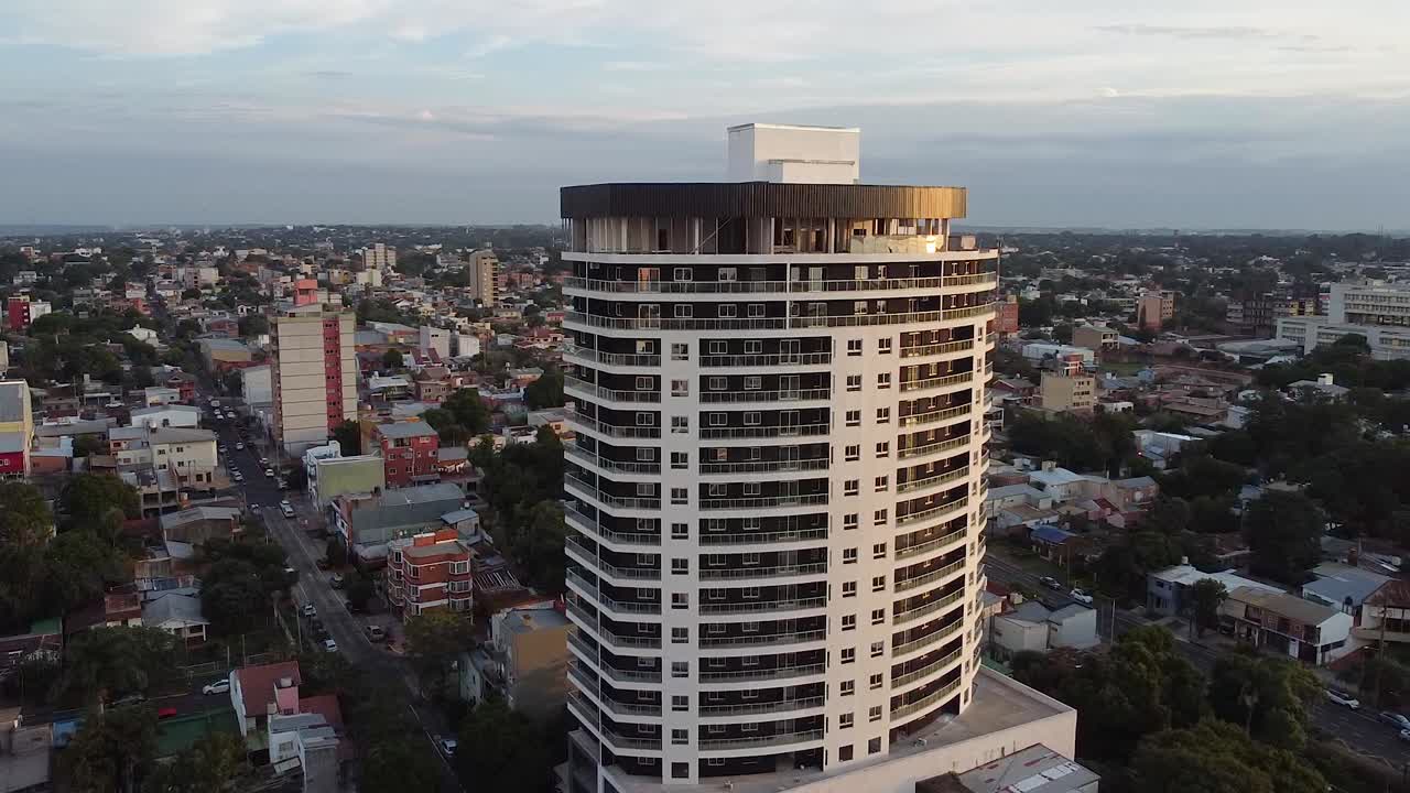 amplia toma aérea de avión no tripulado de un edificio de apartamentos de gran altura con una vista de la ciudad al atardecer