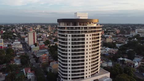 wide drone aerial shot of high rise apartment building with a view of the city at sunset