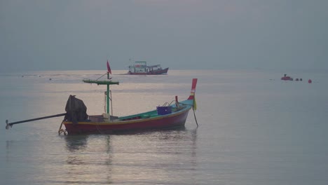 a longtail boat in the calm ocean at sunset