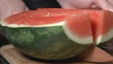 Hand,-Die-Ein-Messer-Hält,-Das-Die-Halbgeschnittene-Wassermelone-Der-Länge-Nach-In-Zwei-Abschnitte-Schneidet---Nahaufnahme