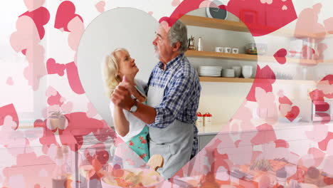 animación de corazones sobre una pareja caucásica senior bailando en la cocina