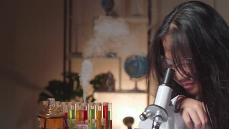 young scientist girl with dirty face looking at microscope and thinking in laboratory