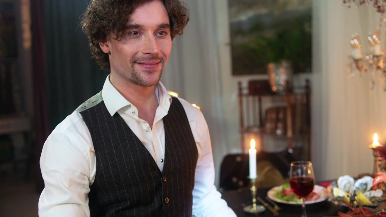 Uomo affascinante che tiene rose rosse a una cena romantica a lume di candela
