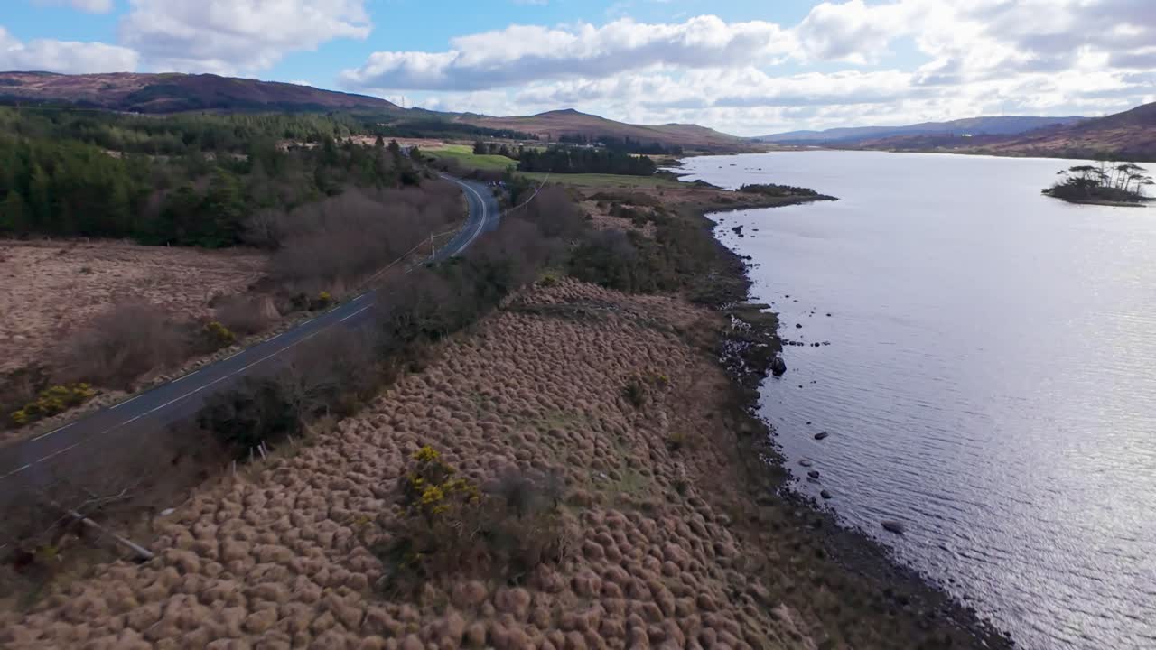 A scenic road winding along a coastline in ireland, surrounded by nature, aerial view